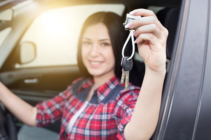 Image of a young woman in a car showing her car keys