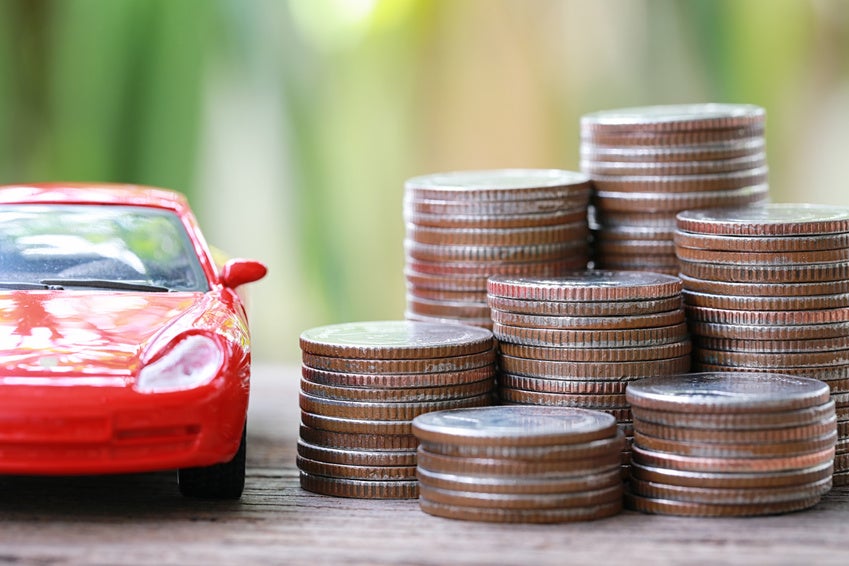 Image of a stack of coins next to a red toy car.