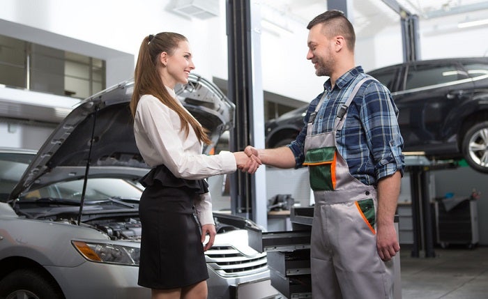 Image of a young woman and a mechanic shaking hands