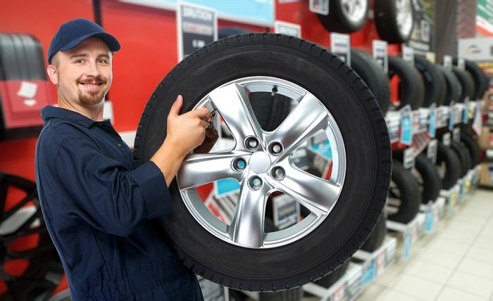 Image of a mechanic holding a tire.