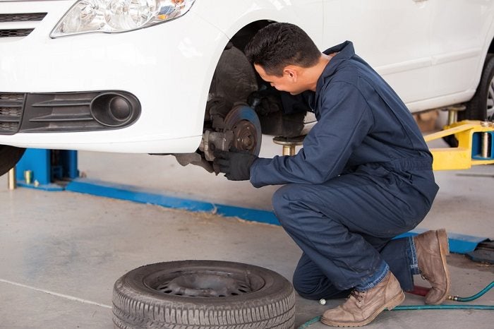 Image of a mechanic working on car brakes.